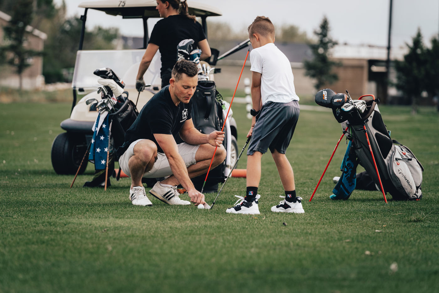 A Tee Box employee working with a group of kids on a golf course in Edmond, OK.